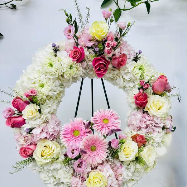 Floral wreath on a black stand with pink and white flowers