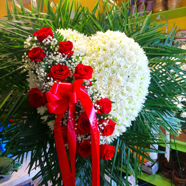Heart-shaped white chrysanthemum arrangement with red roses and ribbon