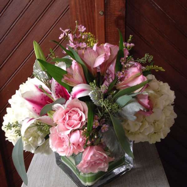 Pink and white floral arrangement in a square glass vase