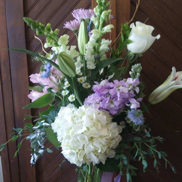 Tall bouquet with white lilies, hydrangea, and lavender flowers in a glass vase