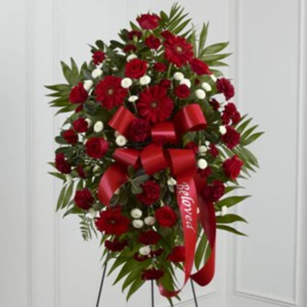 Standing spray of red flowers with a red ribbon on an easel