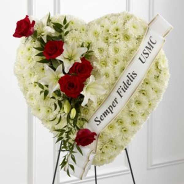 Heart-shaped funeral wreath with red roses and white flowers on a stand