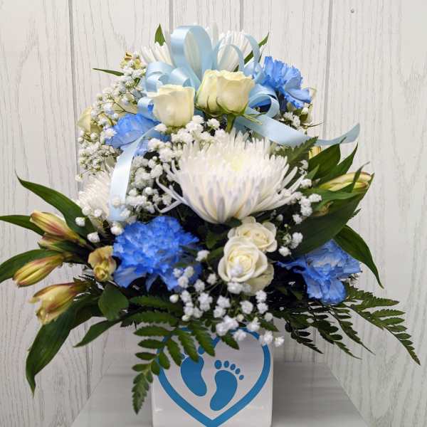 Blue and white floral arrangement in a square vase with ribbon