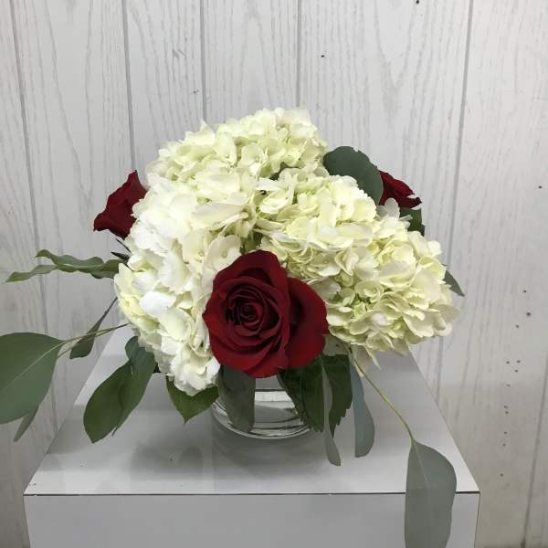 White hydrangeas and red roses in a clear glass vase