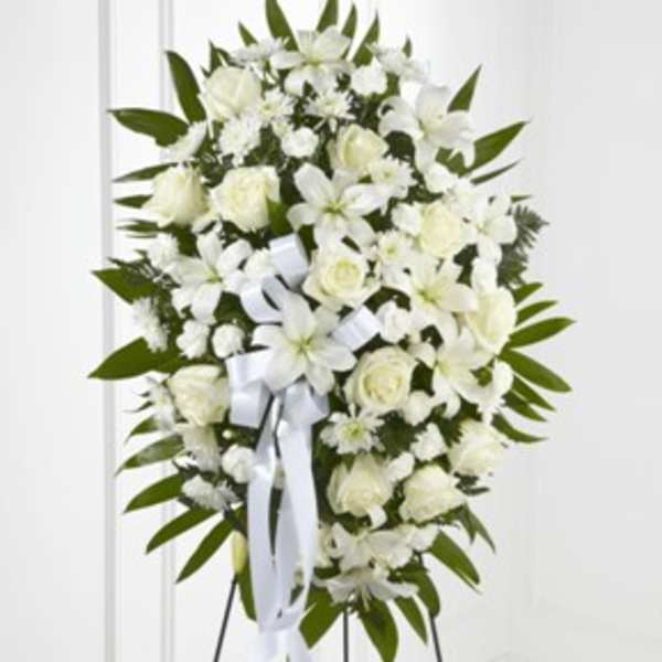 White funeral spray with lilies and roses on a stand