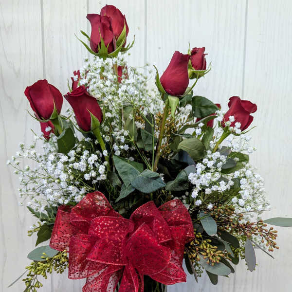 Red roses in a glass vase with a red bow and a box of truffles