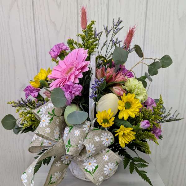 Mixed bouquet in a white container with a daisy-print bow