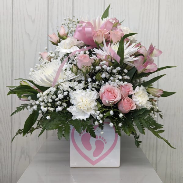 Pink and white floral arrangement in a white box with a pink footprint design