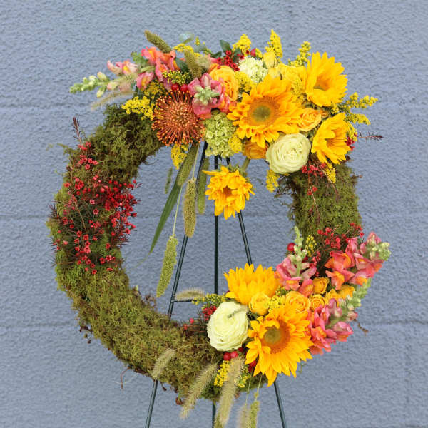 Floral wreath with sunflowers and mixed blooms on a metal stand