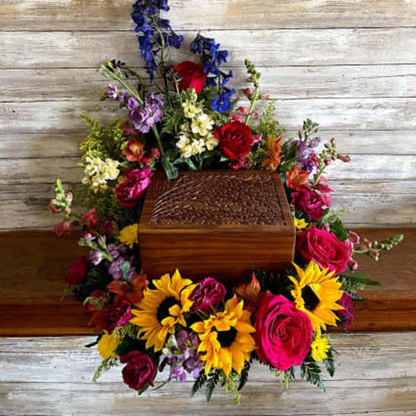 Colorful floral arrangement around a wooden urn on a rustic background