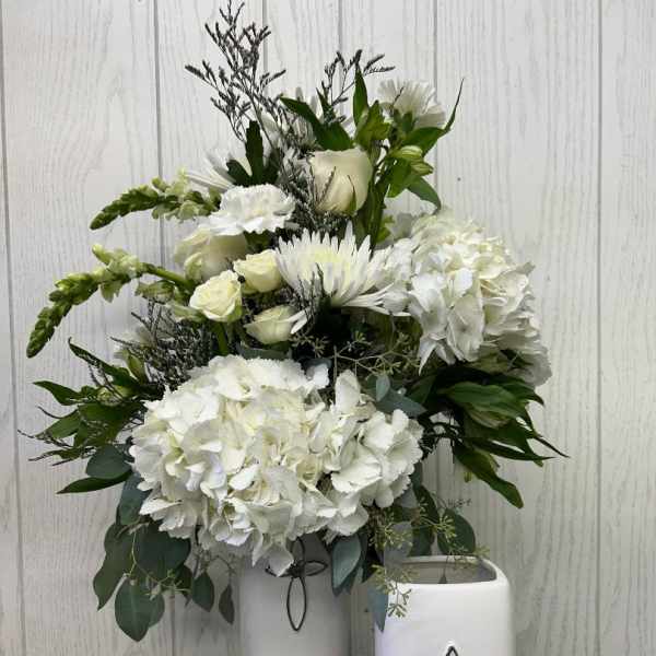 White floral arrangement in two white vases with cross accents