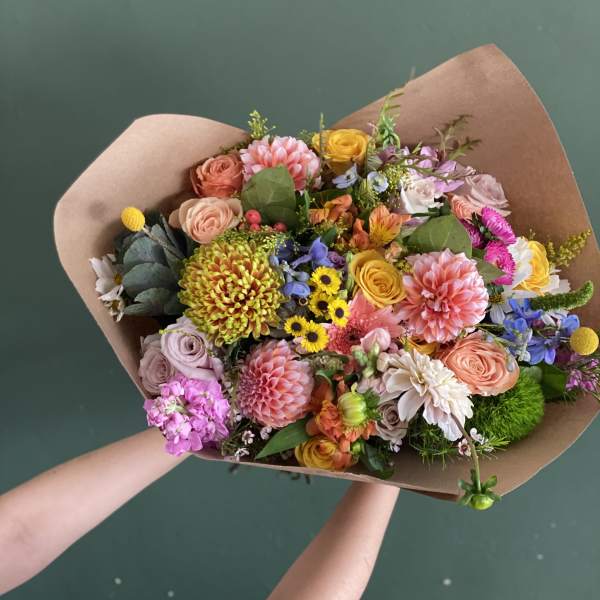 Mixed bouquet of colorful flowers wrapped in brown paper