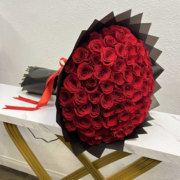 Large bouquet of red roses wrapped in black paper with a red ribbon