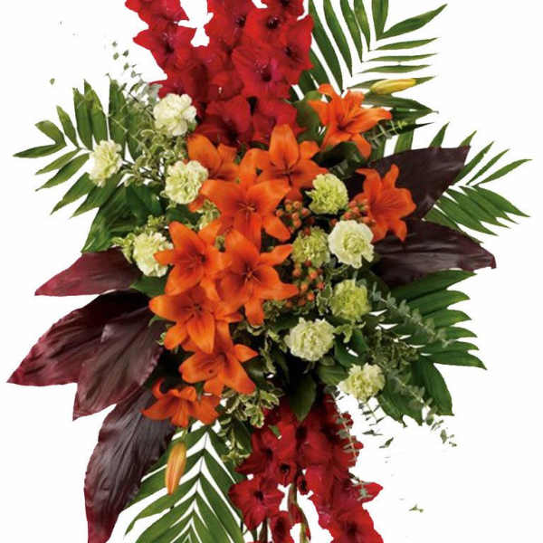 Tall standing spray of red gladiolus, orange lilies, and light green blooms with bold foliage.