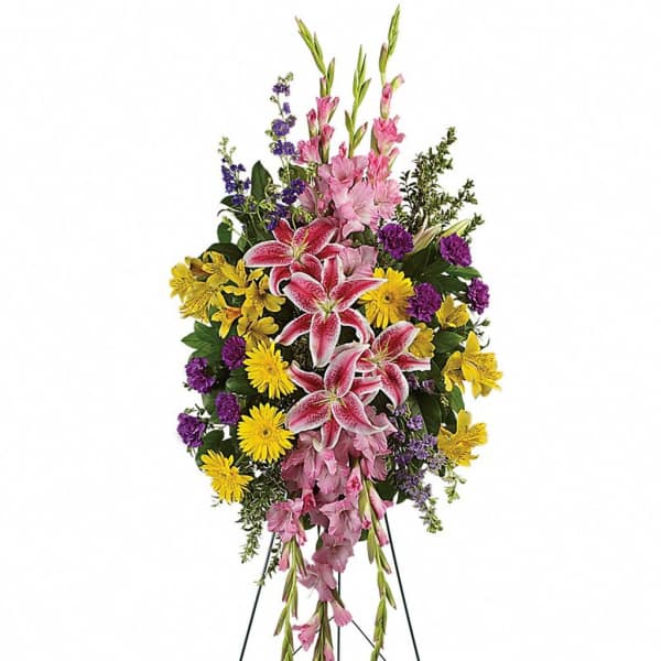 Standing spray of pink lilies, yellow daisies, and purple flowers on a wire easel