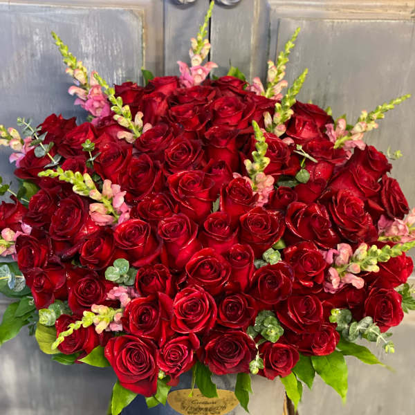 Large bouquet of red roses with pink snapdragons in a gray vase