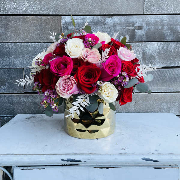 Bouquet of red, pink, and white roses in a gold vase