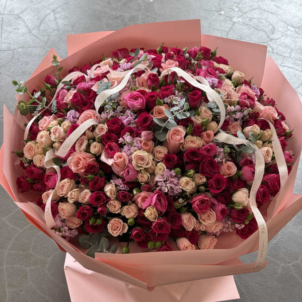 Large bouquet of pink and red roses wrapped in blush paper