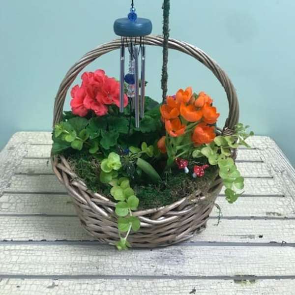 Basket arrangement with pink and orange flowers and a hanging wind chime