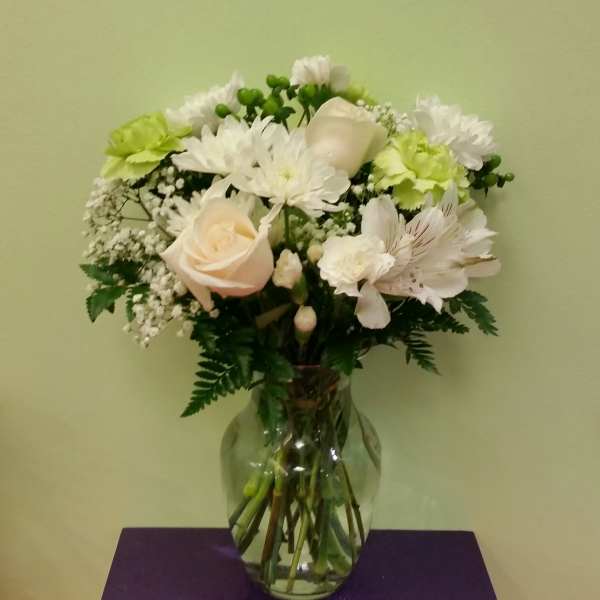 White and pale peach flowers arranged in a clear glass vase
