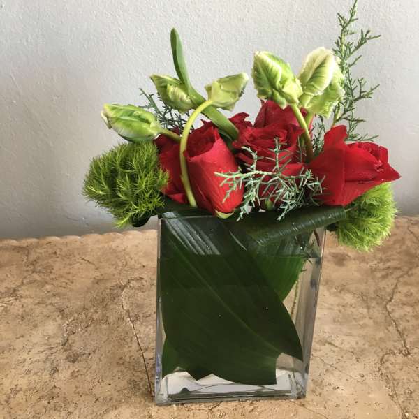 Red roses in a clear glass vase with green accents