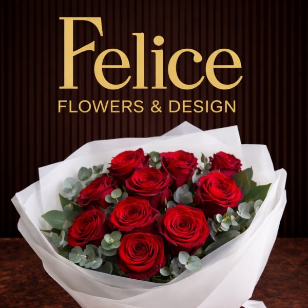 Bouquet of red roses wrapped in white paper with a burgundy ribbon