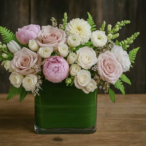 Pink and white roses arranged in a green glass vase
