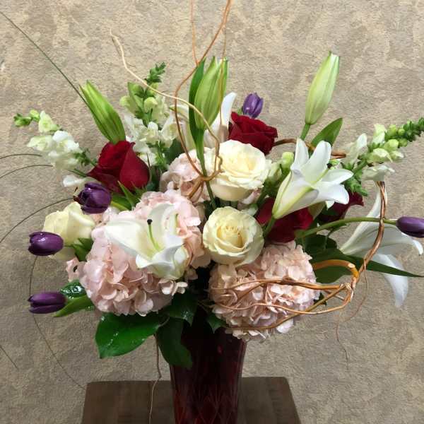 Bouquet of roses, lilies, and hydrangeas in a red vase