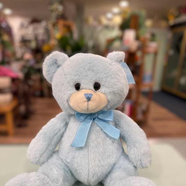 Light blue teddy bear with a ribbon bow sitting on a counter