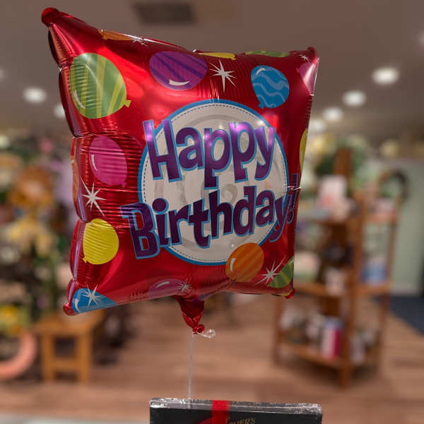 Birthday balloon with a box of chocolates tied below it