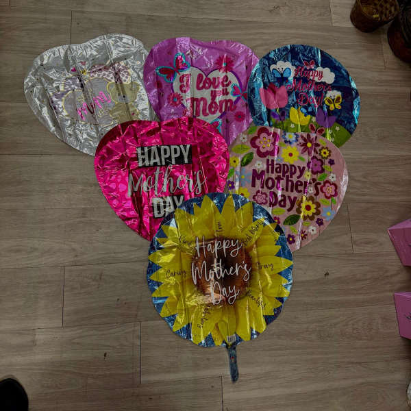 Mother's Day heart-shaped foil balloons arranged on a floor