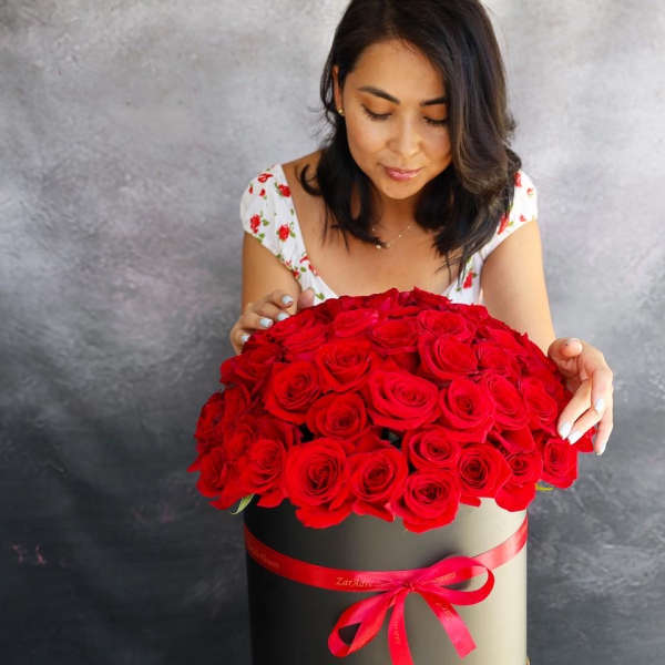 Woman holding a large box of red roses with a ribbon