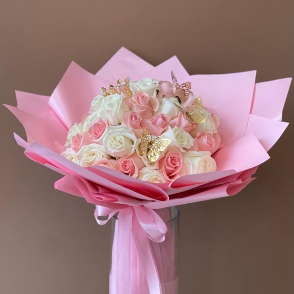 Bouquet of pink and white roses wrapped in pink paper with butterfly picks
