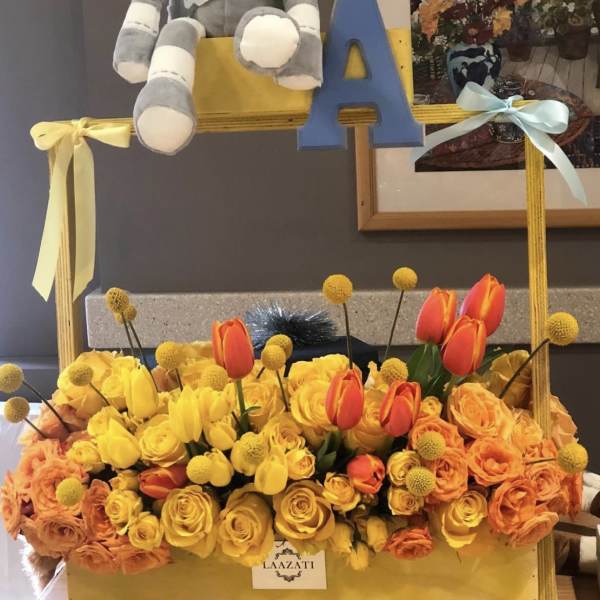Yellow and orange flower arrangement with a plush elephant and blue letter A