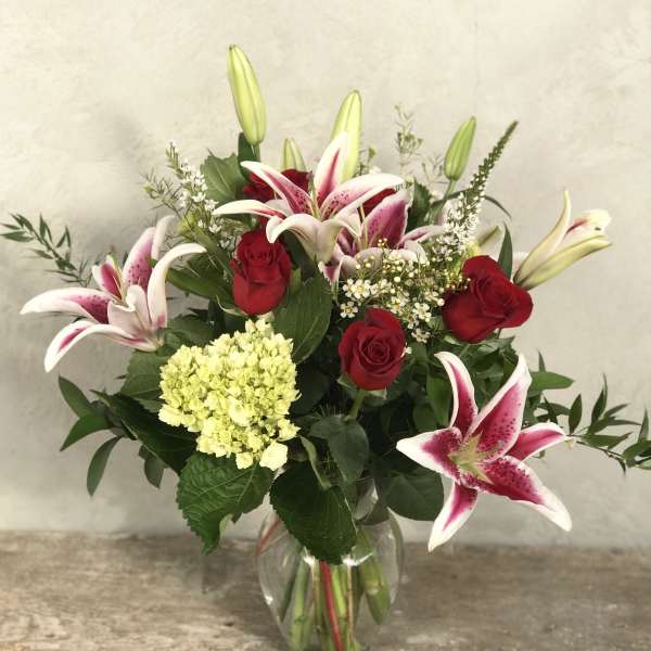 Bouquet of pink lilies and red roses in a clear glass vase