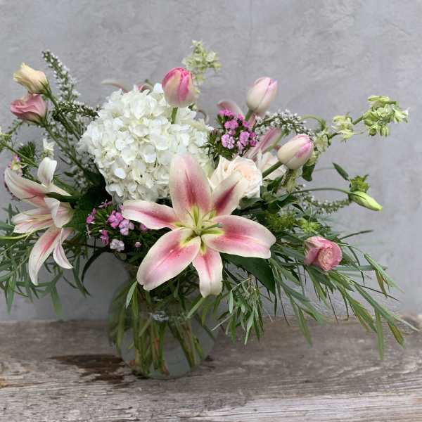 Pink and white lily bouquet in a glass vase with white hydrangea