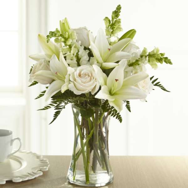 White lilies and roses arranged in a clear glass vase