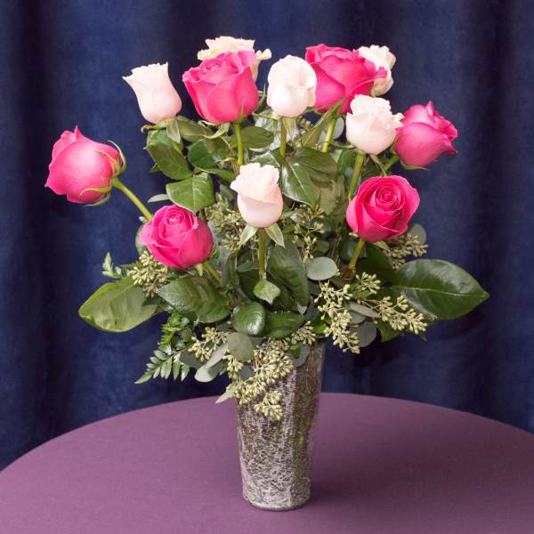 Pink and white roses arranged in a tall vase