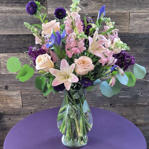 Mixed bouquet of pink and purple flowers in a clear glass vase