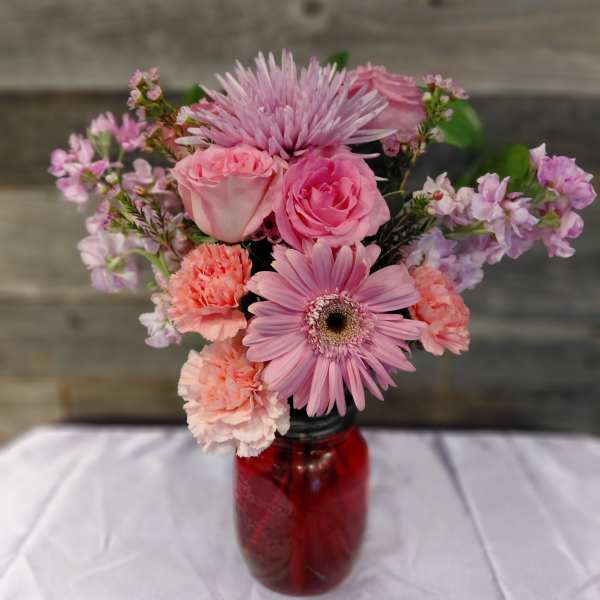 Pink mixed bouquet in a red glass jar vase