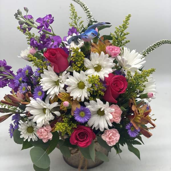 Mixed bouquet of roses, daisies, and purple flowers in a vase