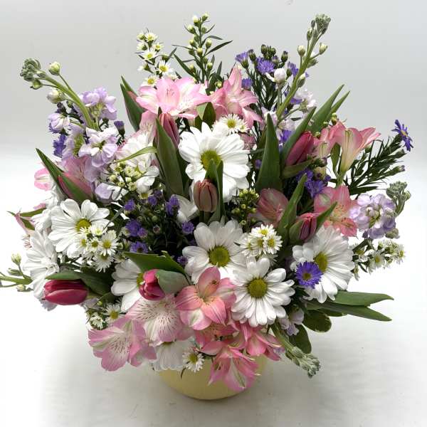 Mixed bouquet of pink lilies, white daisies, and purple filler flowers in a vase