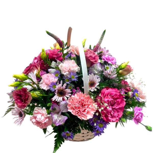 Basket arrangement of pink carnations, roses, and purple daisies with mixed pastel flowers.