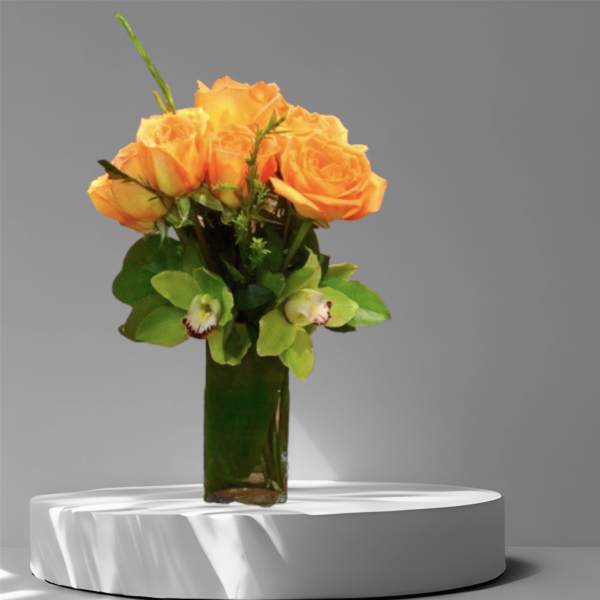 Orange roses in a tall glass vase with green orchids