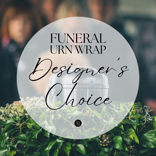 Funeral urn wrap with greenery and pale flowers around a silver urn