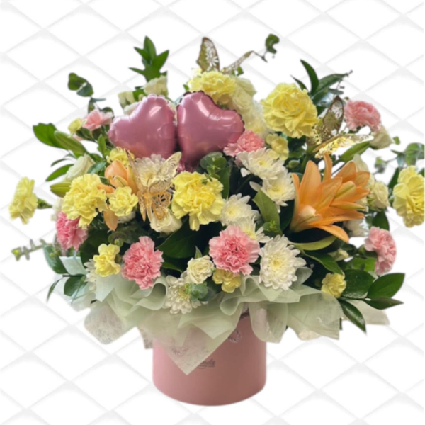 Pink heart balloons in a mixed flower arrangement in a pink box