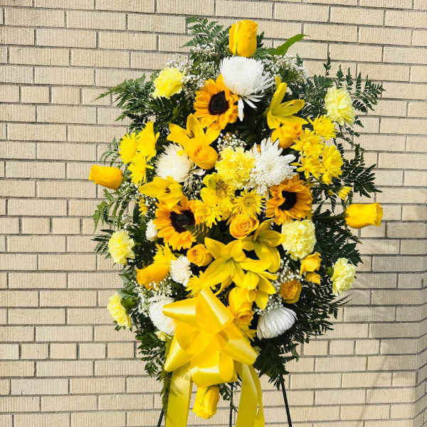 Yellow and white floral standing spray with a large ribbon bow