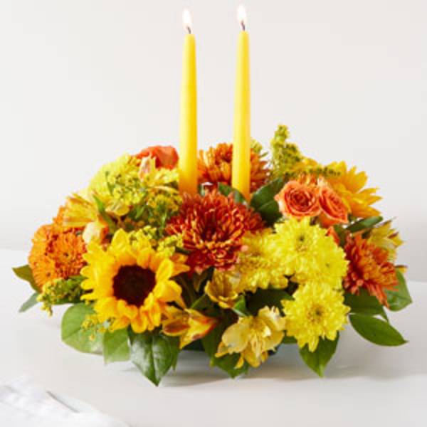 Yellow and orange floral centerpiece with two tall candles