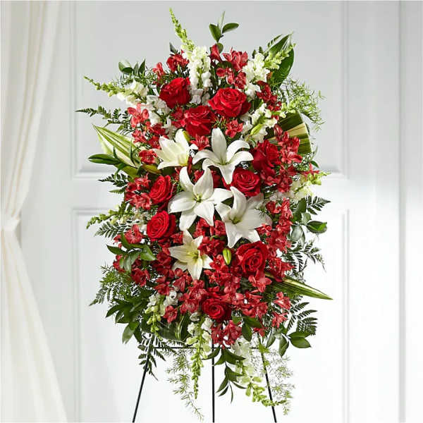 Standing floral spray with red roses and white lilies on a black easel