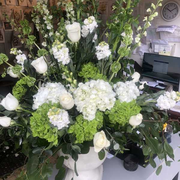 Tall white and green floral arrangement in a pedestal vase